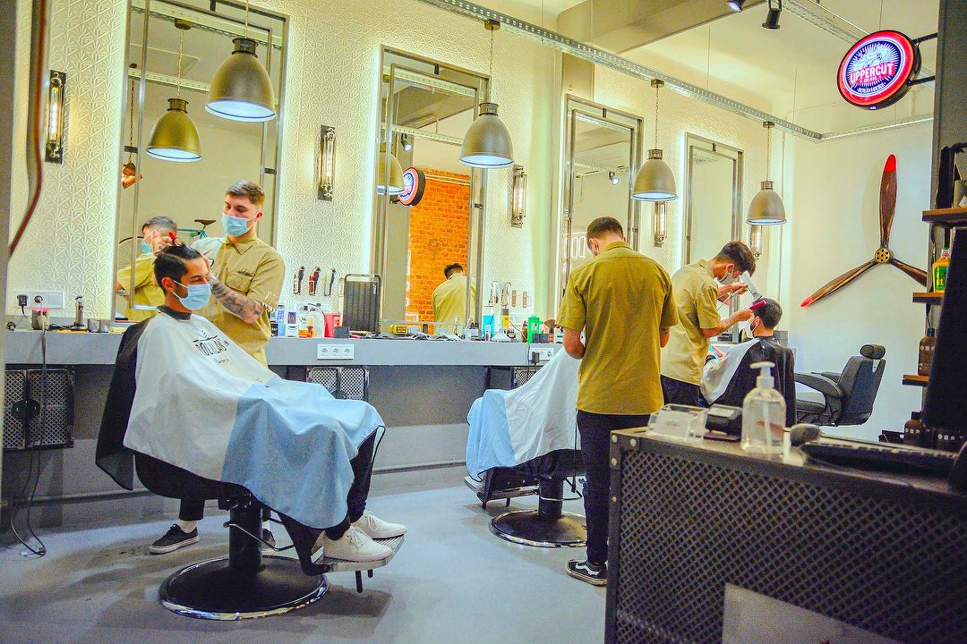 Hipster barbero hombre peluquero cortando el cabello y dando forma a la  barba de un hombre en un sillón