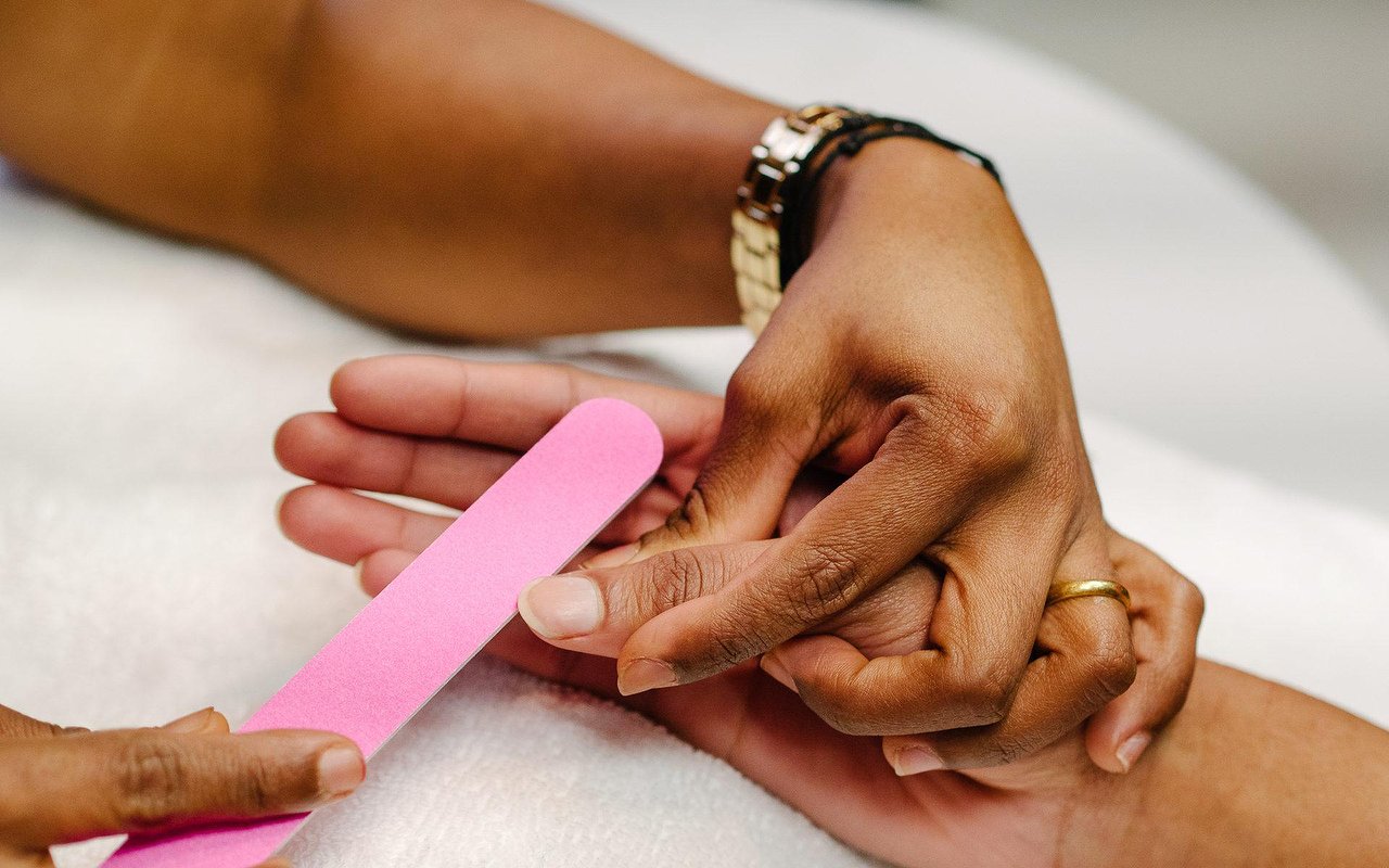 Belle mani di donna e lampada per unghie sul tavolo da vicino